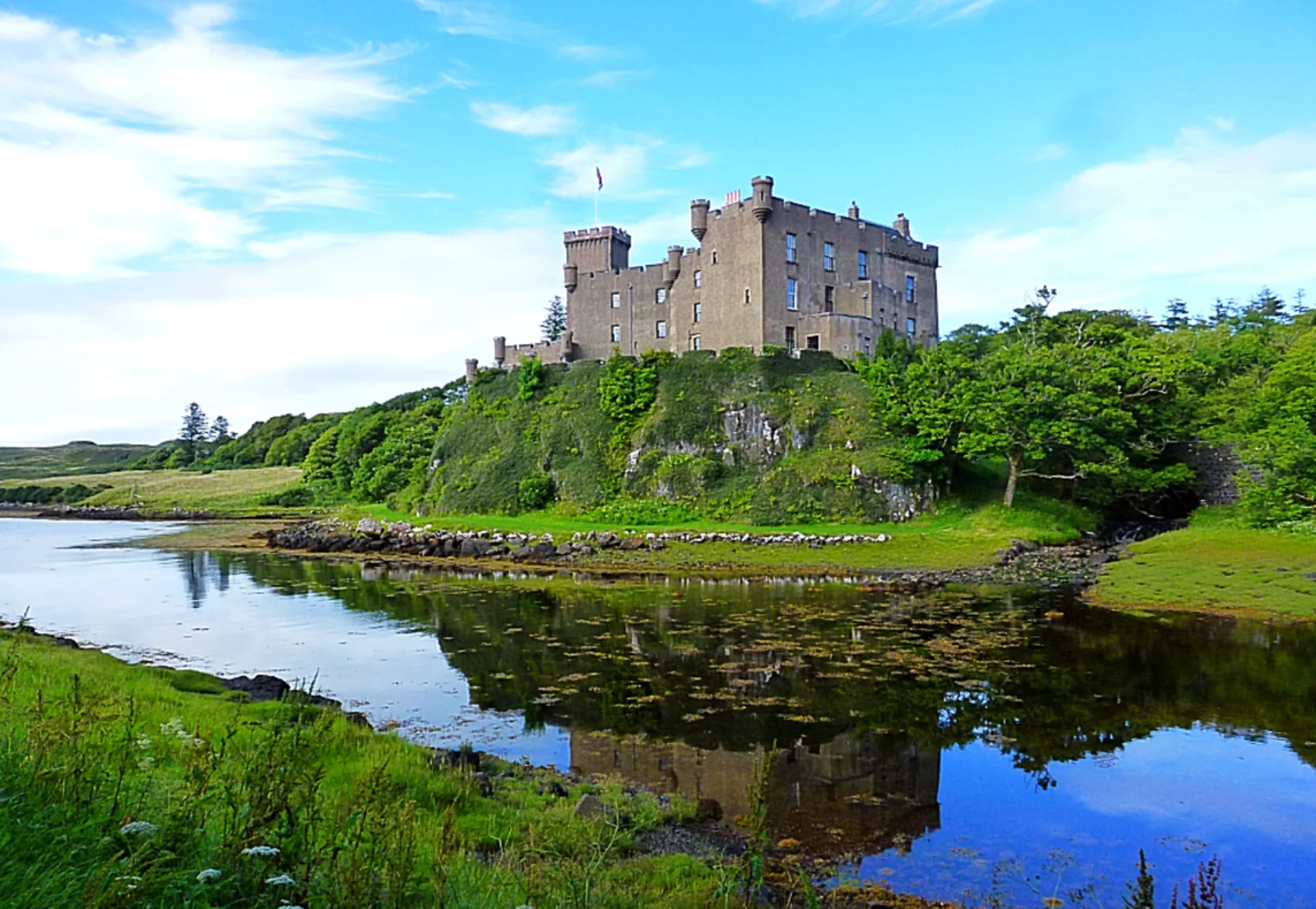 A castle sits on top of a hill near the water.