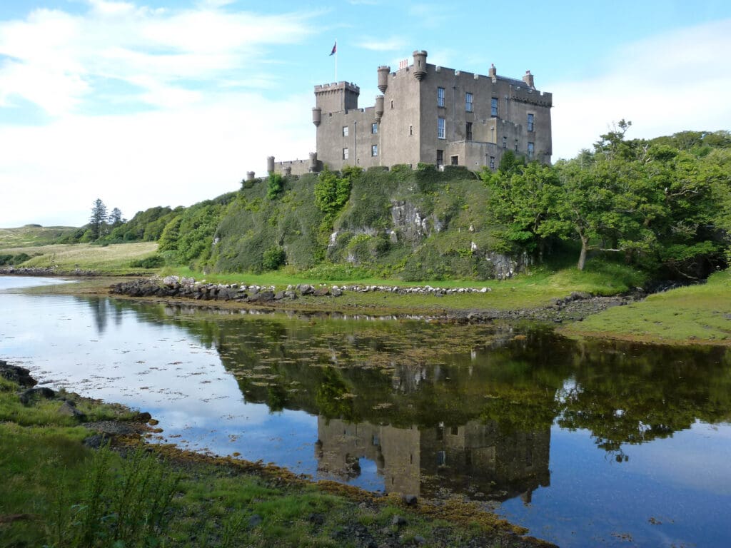 A castle sits on top of a hill near the water.