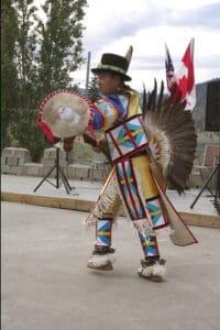 A man in native american costume holding a fan.